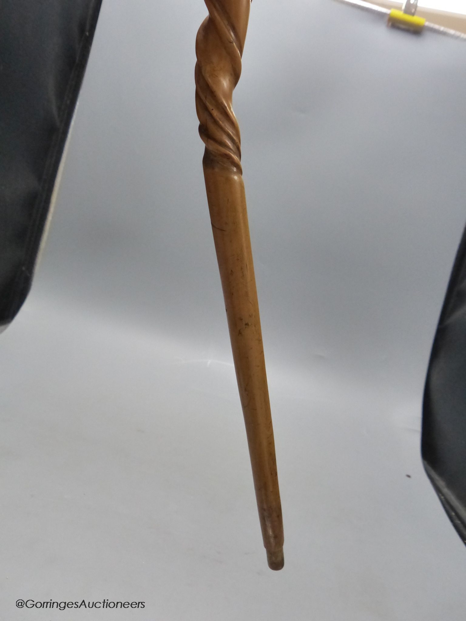 A carved wood walking stick in the style of a narwal tusk